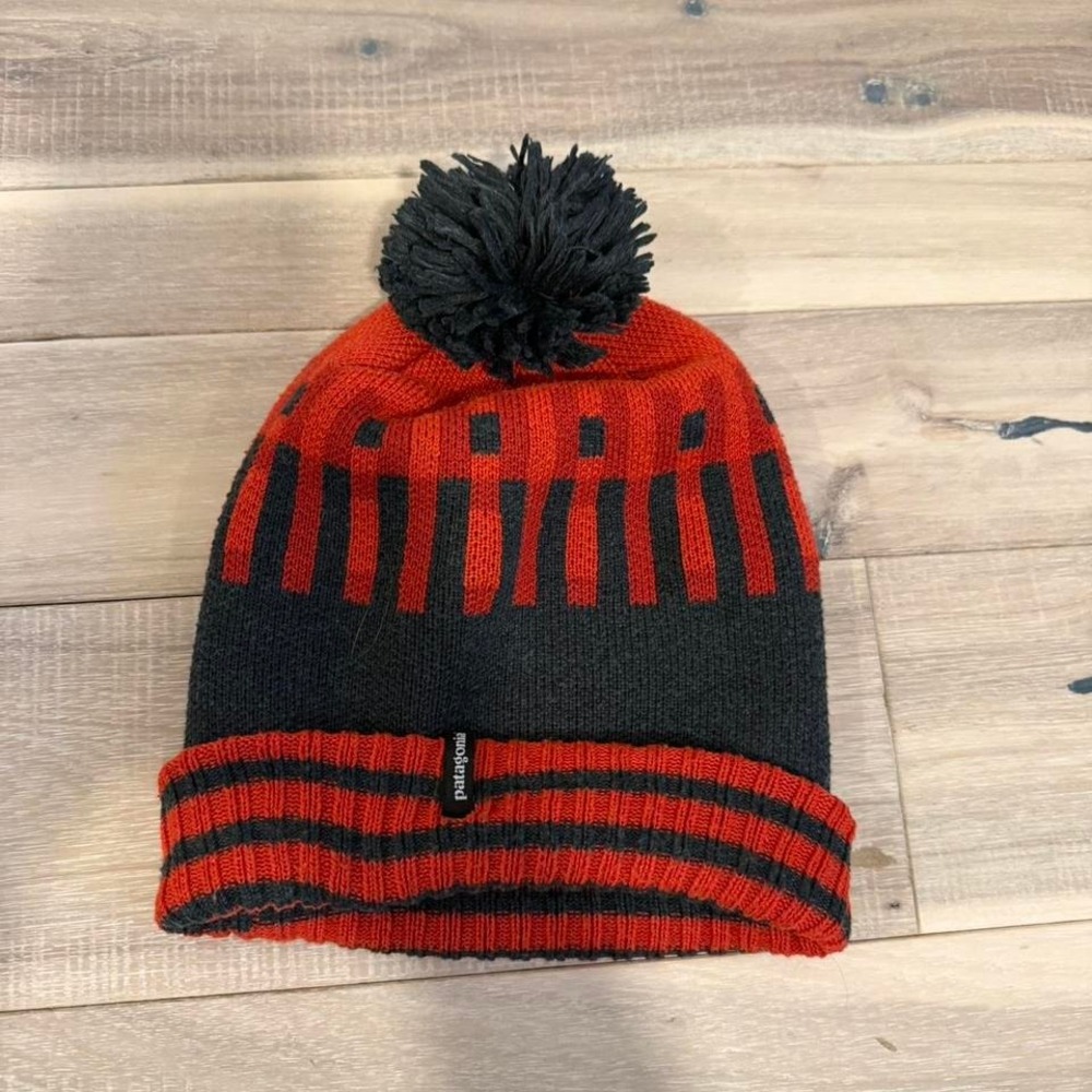 Patagonia orange and black striped beanie with pom pom